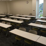 A view of the back of the classroom showing rows of tables and chairs for student seating.