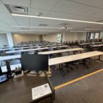 A view from the front of the classroom showing rows of tables and chairs.