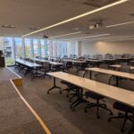 Picture of the classroom from the side showing rows of tables and chairs with roughly 100 seats.
