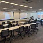 Photo of a classroom looking towards the front of the room showing a two projector screen system.