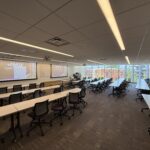 Photo of a classroom looking towards the front of the room showing a two projector screen system.