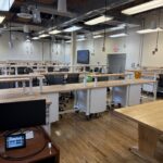 Image take from the front of the classroom that shows rows of student work benches.