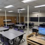 View of the classroom from the front showing clusters of tables.