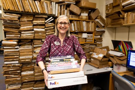 Woman in a mail room carrying FedEx packages