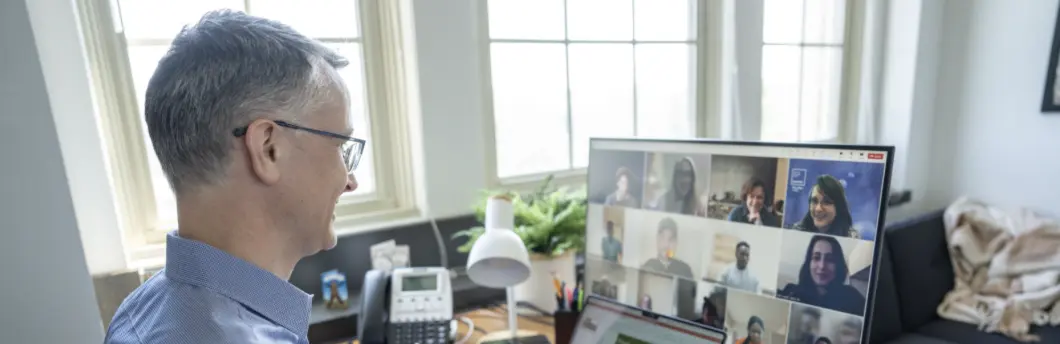 Man looking at computer monitor see other people joining him in a video conference