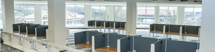interior of carrier library, featuring large windows looking out on hillcrest and d-hall with study carrels and empty bookshelves in the foreground