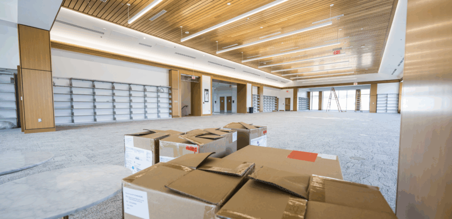 photo of the grand reading room in carrier library, with bookshelves visible and large windows and a beautiful wood ceiling; the room is empty except for moving boxes