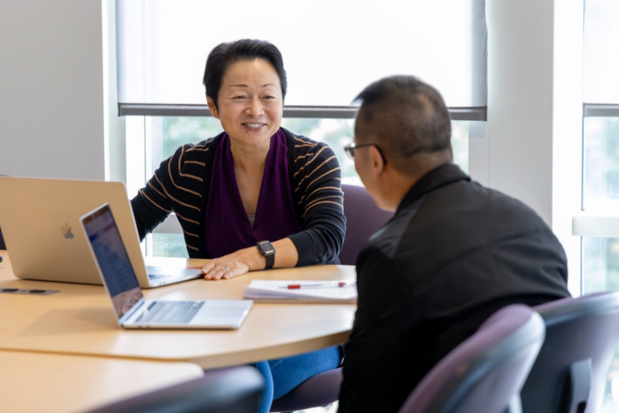 two faculty talking at a desk