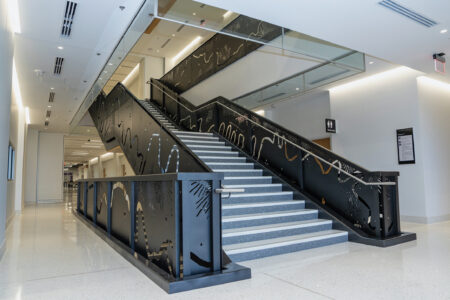 Looking up a large staircase with carved black metal railing.